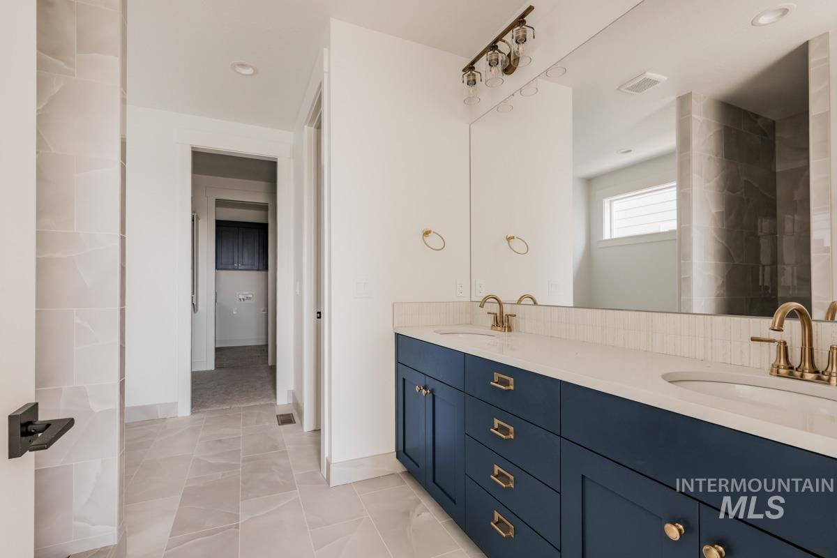 Bathroom featuring double vanity, light tile patterned floors, and recessed lighting