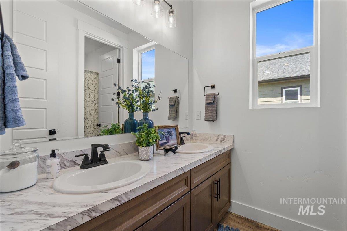 Bathroom with double vanity, healthy amount of natural light, and dark wood finished floors