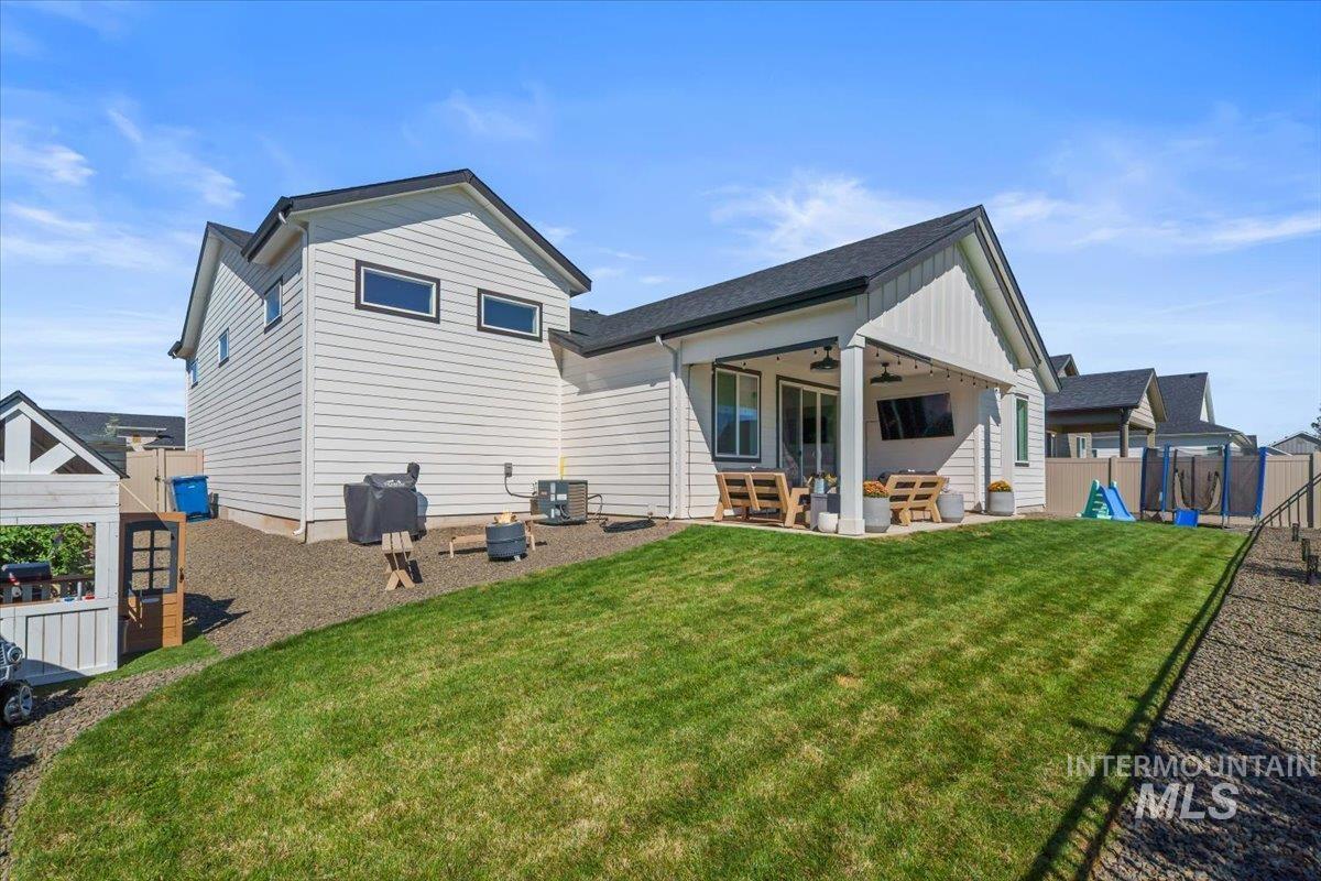 Rear view of house with a playground, ceiling fan, a patio area, an outdoor hangout area, and board and batten siding