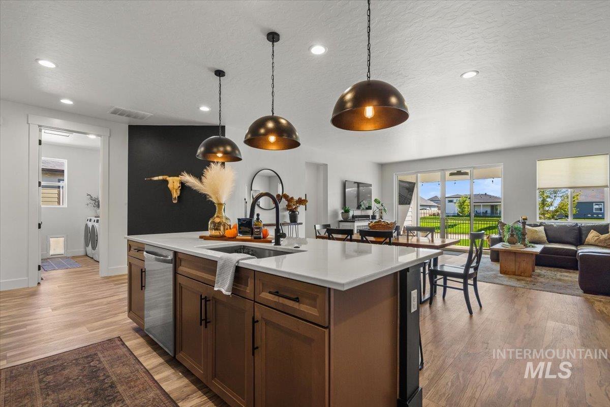 Kitchen featuring open floor plan, a textured ceiling, decorative light fixtures, recessed lighting, and light wood-type flooring
