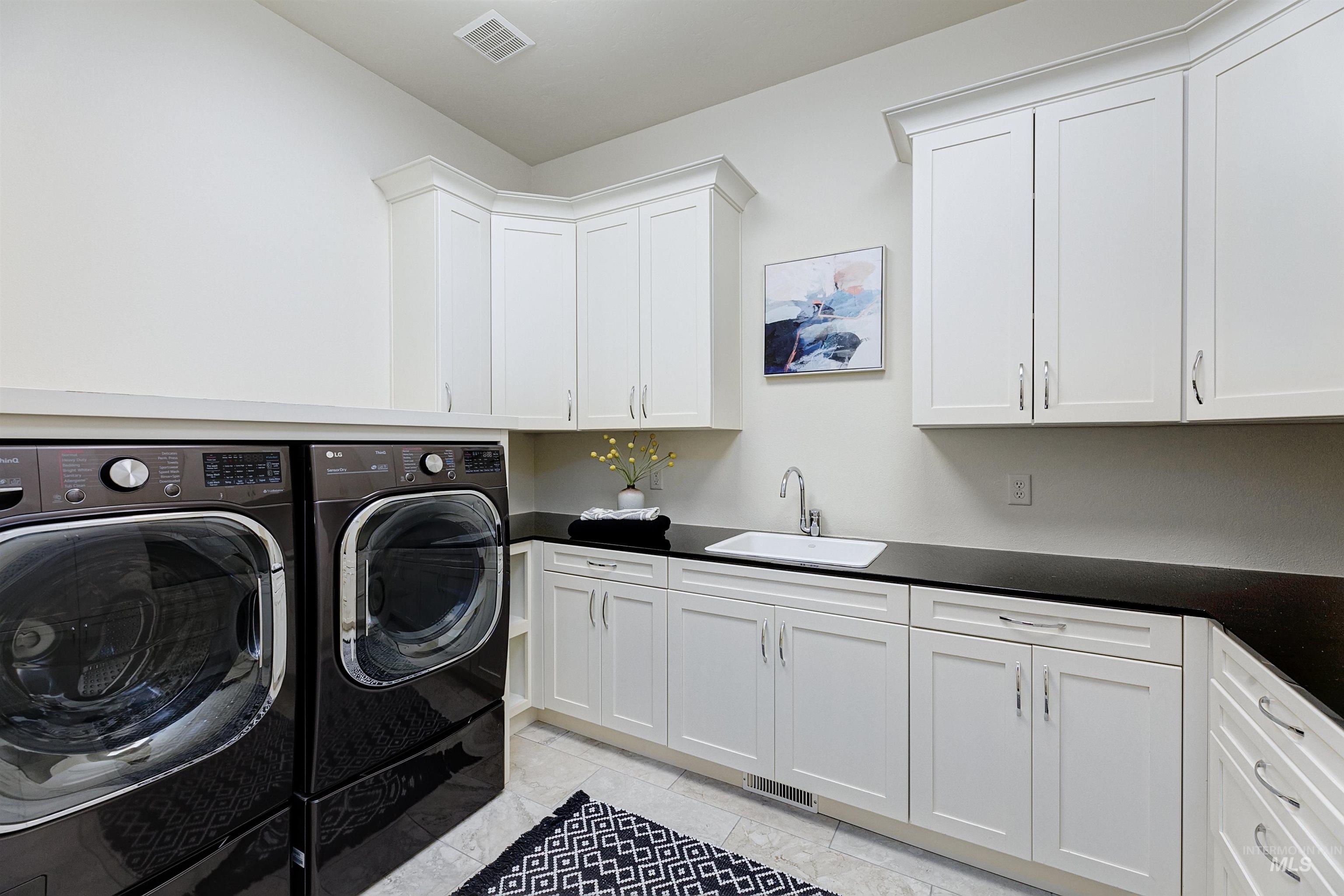 Laundry area featuring washer and dryer, cabinet space, utility sink, and tile.