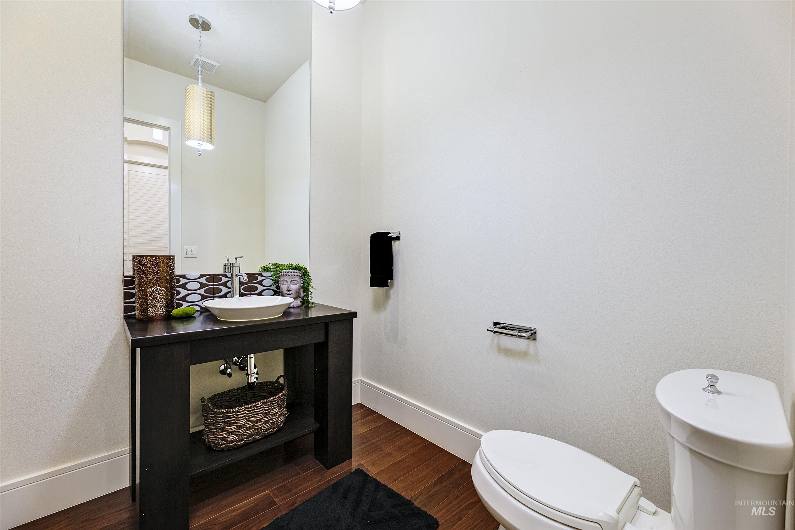 Half bathroom featuring wood finished floors and vanity.