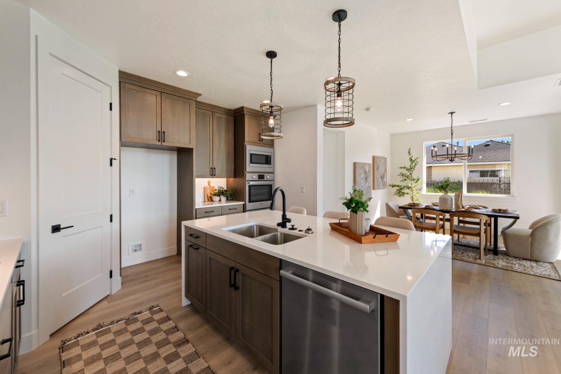 Kitchen featuring hanging light fixtures, stainless steel appliances, light wood finished floors, light stone counters, and recessed lighting