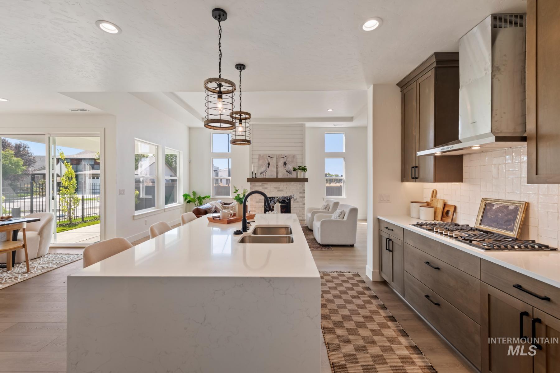 Kitchen with open floor plan, a large fireplace, backsplash, pendant lighting, and light wood-style flooring