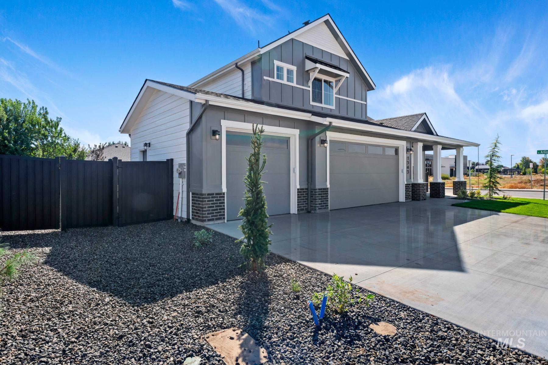View of side of home featuring board and batten siding, brick siding, concrete driveway, covered porch, and a garage