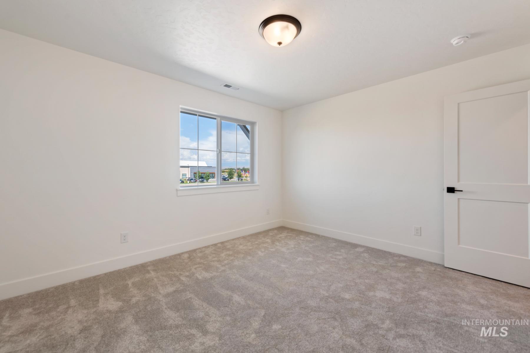 Spare room with baseboards and light colored carpet
