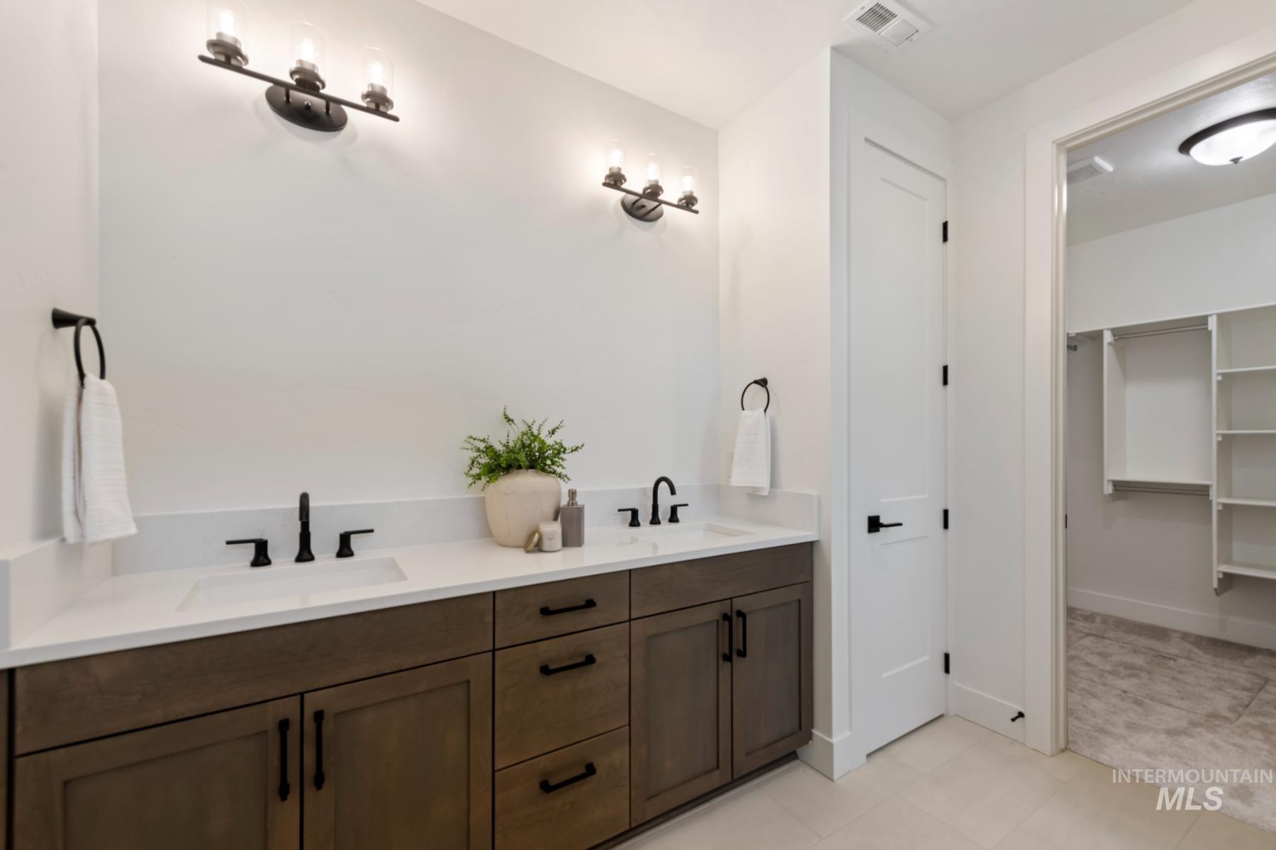 Bathroom featuring double vanity and a walk in closet