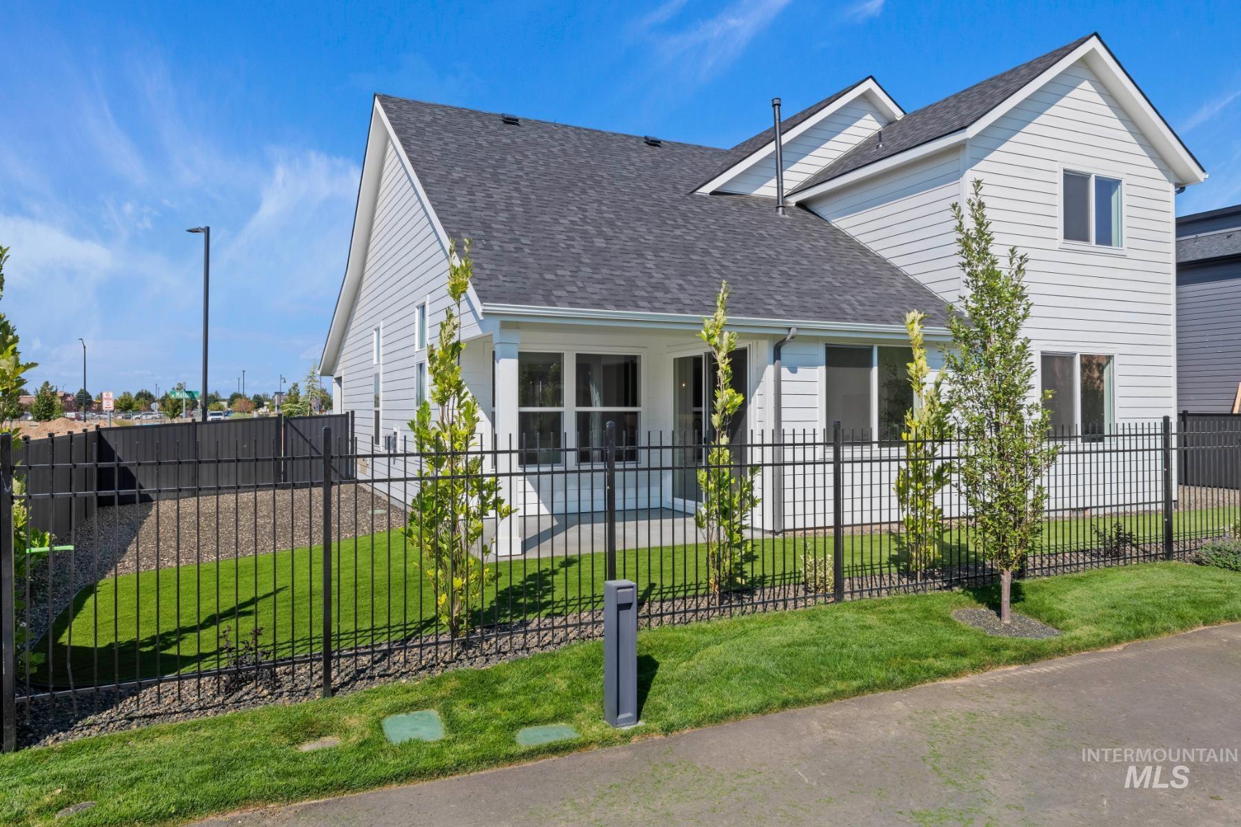 View of front facade with a shingled roof, a fenced front yard, and a patio