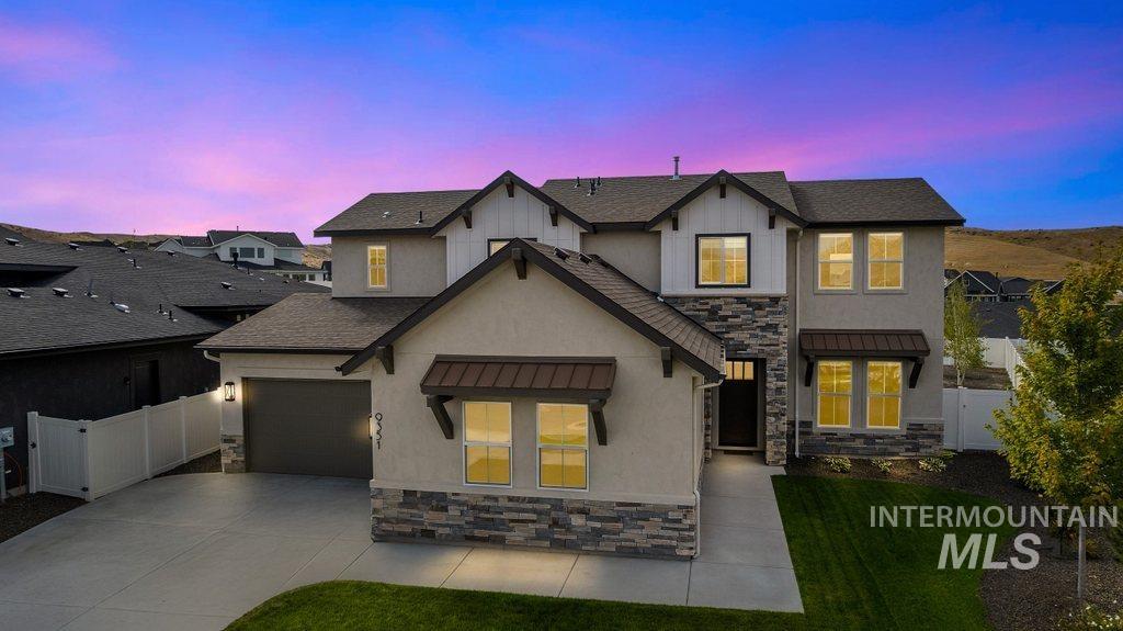 View of front of house featuring stone siding, a standing seam roof, a metal roof, stucco siding, and driveway