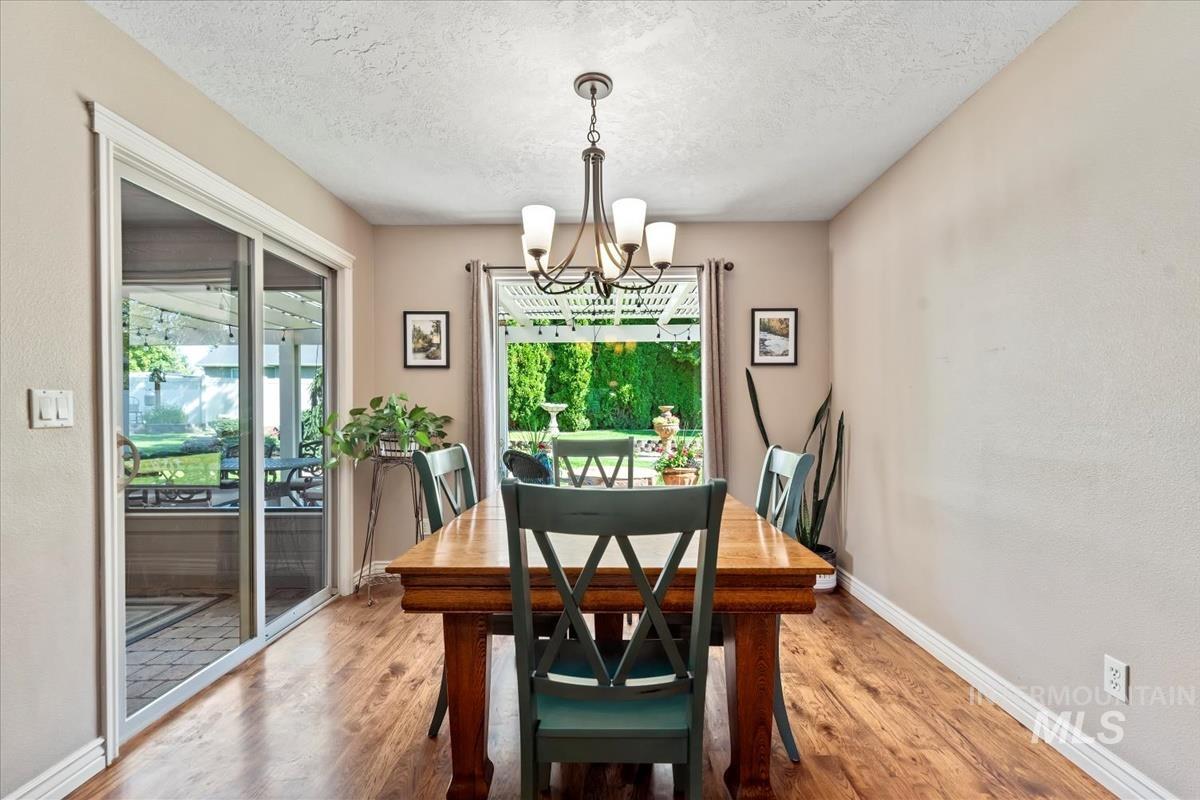 Dining space featuring wood finished floors, a textured ceiling, healthy amount of natural light, and a chandelier
