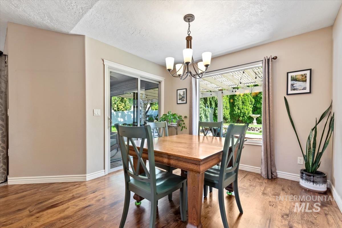 Dining space with wood finished floors, a textured ceiling, and a chandelier