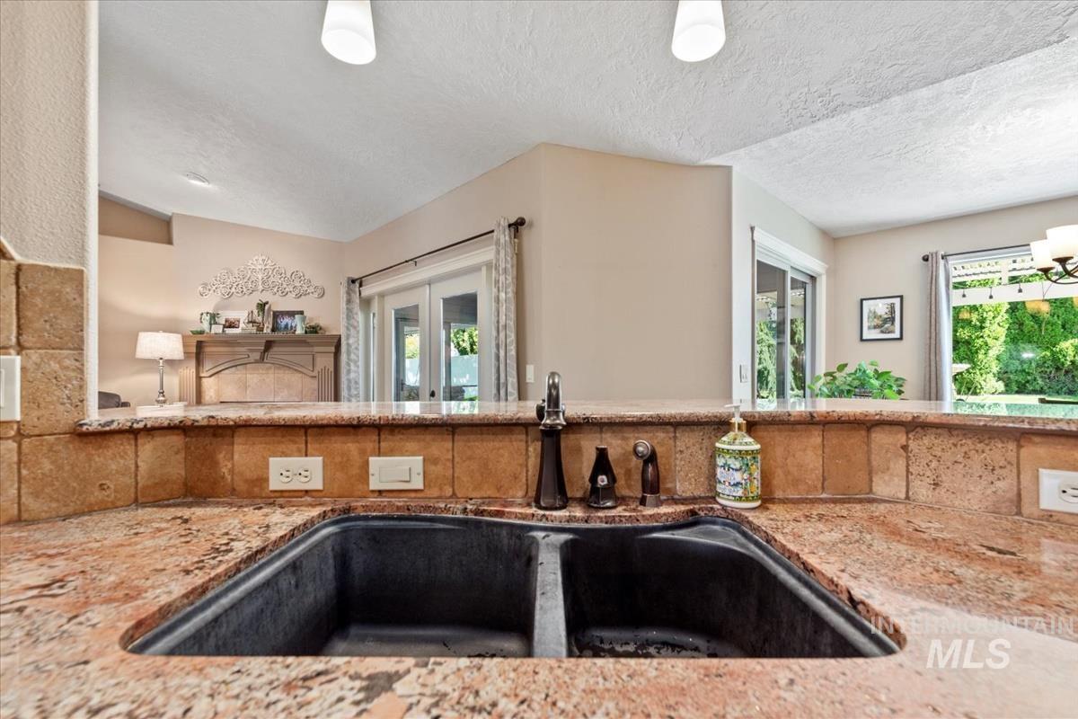 Kitchen featuring light stone counters, plenty of natural light, a textured ceiling, and open floor plan