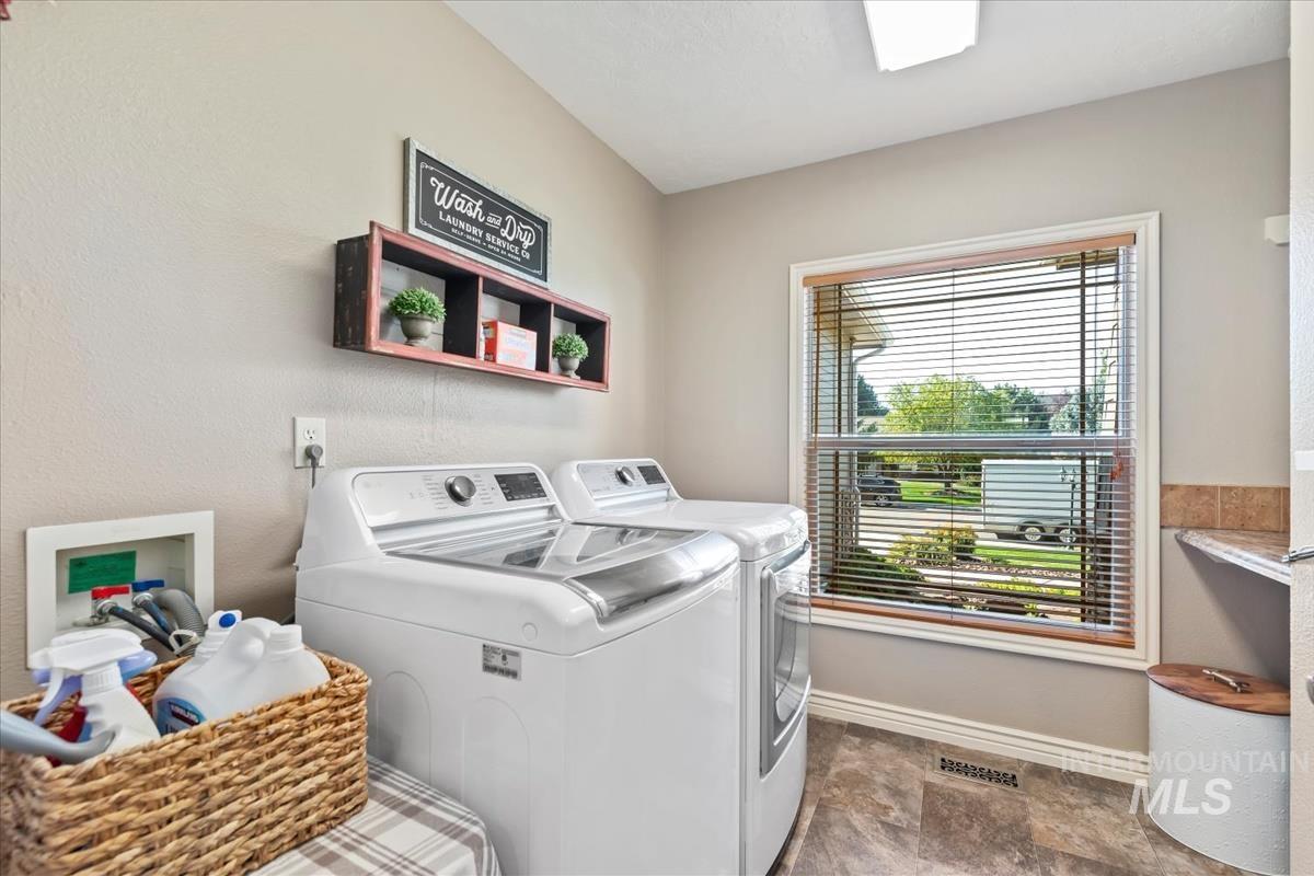 Laundry area with independent washer and dryer, stone finish floors, and a textured wall