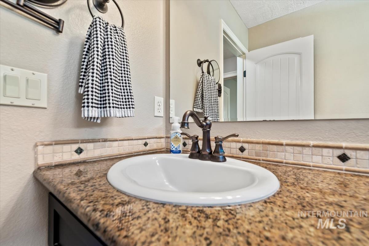 Bathroom with a textured wall, vanity, and a textured ceiling