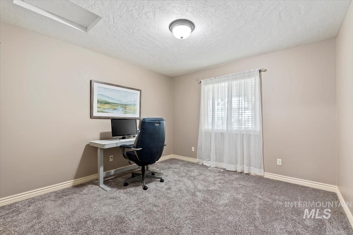 Home office with carpet flooring, a textured ceiling, and attic access