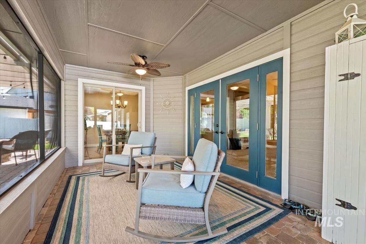 Sunroom featuring wood walls, french doors, a ceiling fan, and a patio area