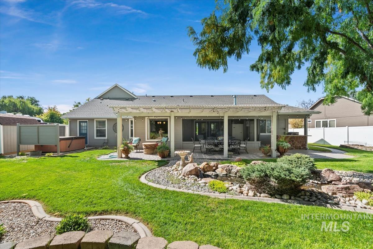 Back of house with a hot tub, a patio area, a pergola, and a shingled roof