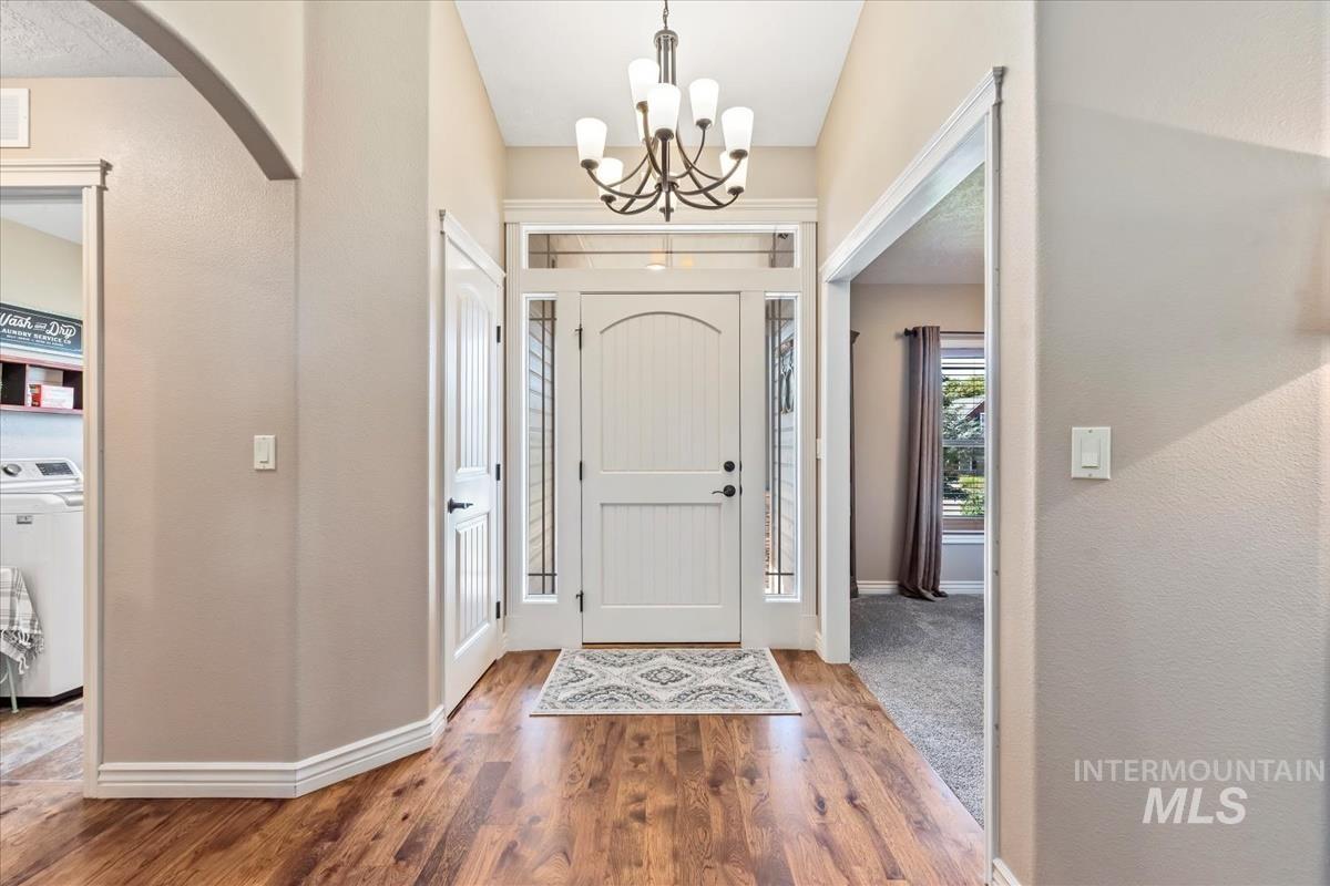 Entryway featuring arched walkways, washer / dryer, wood finished floors, and a chandelier