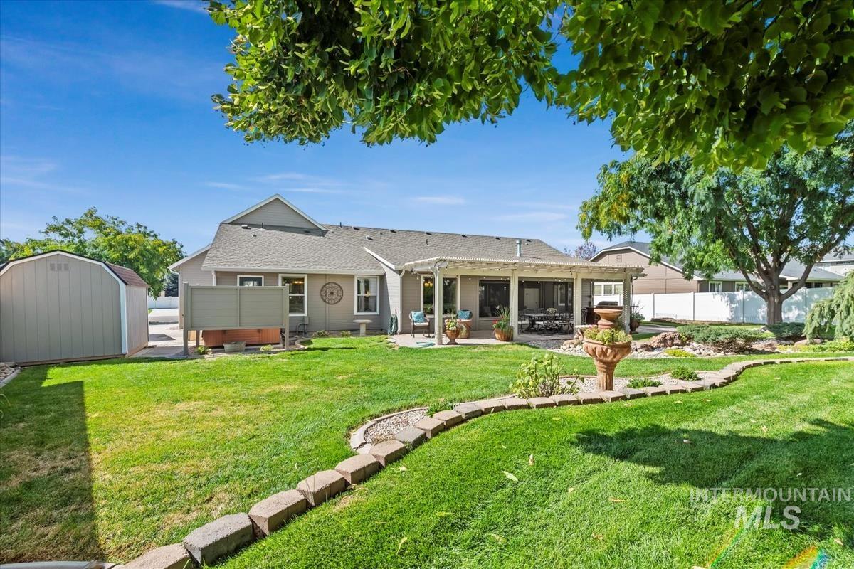 Back of property featuring a storage shed, a hot tub, a fenced backyard, a patio, and a shingled roof