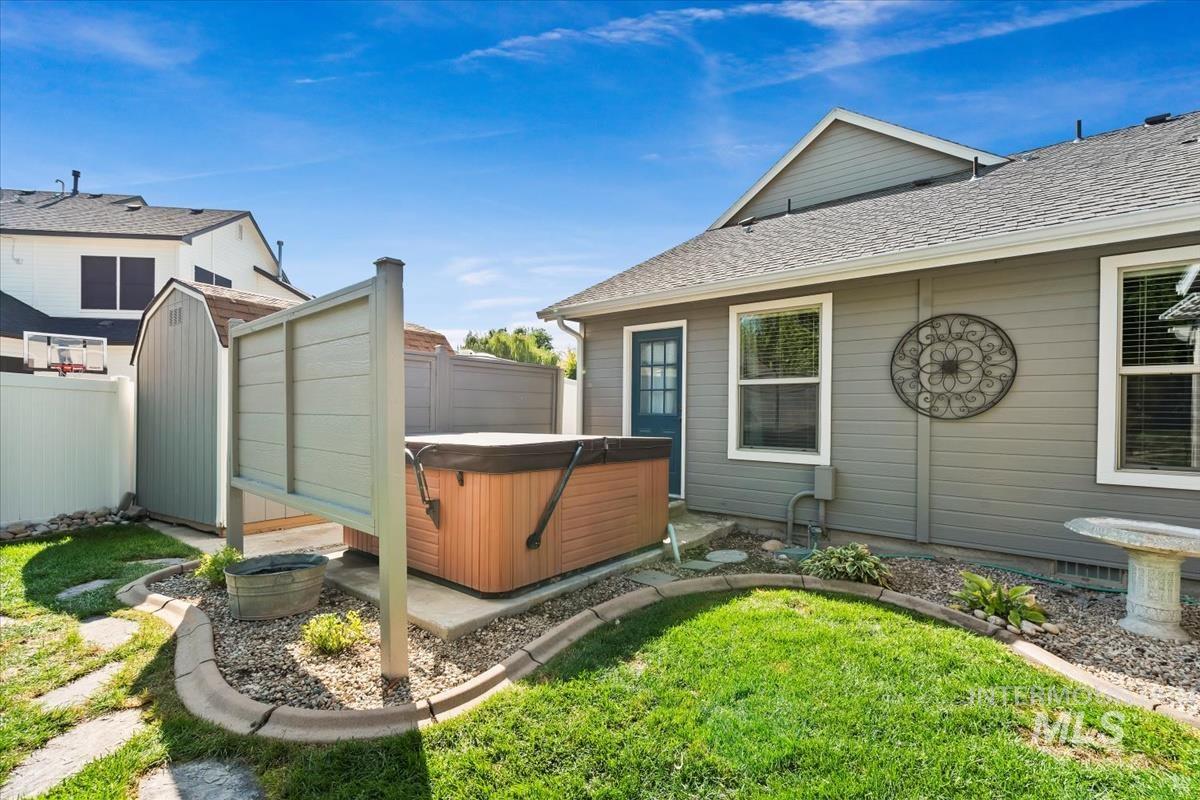 Rear view of property with roof with shingles and a hot tub