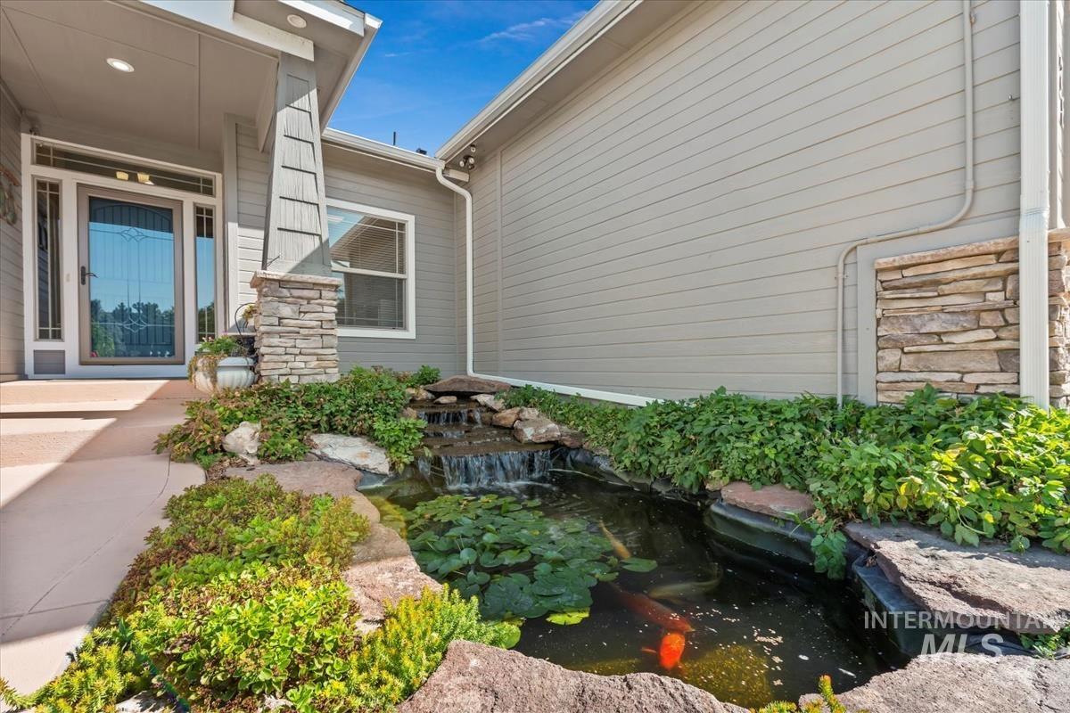 View of side of home featuring stone siding and a small pond