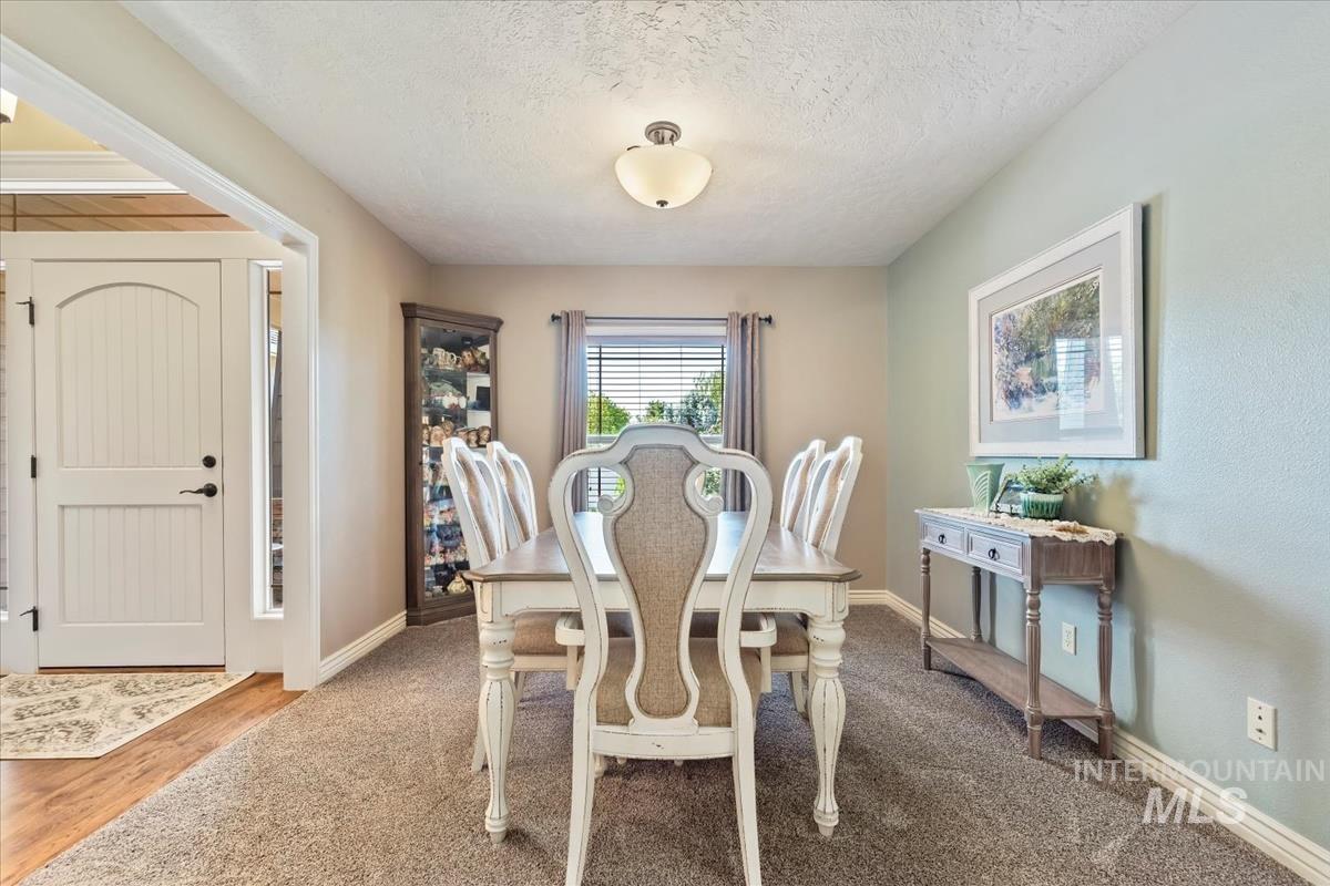 Carpeted dining room with a textured ceiling and baseboards