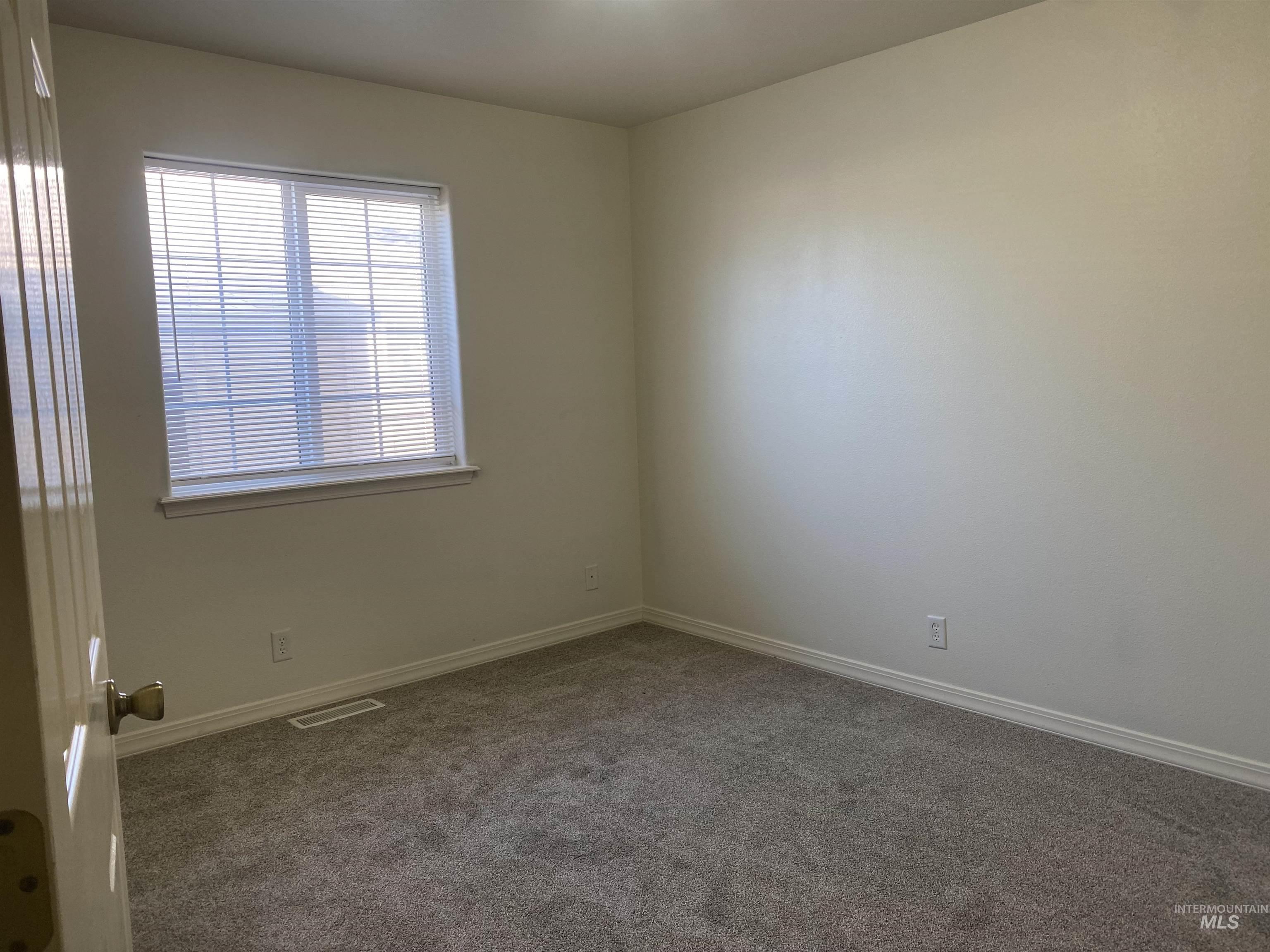 Carpeted spare room featuring baseboards