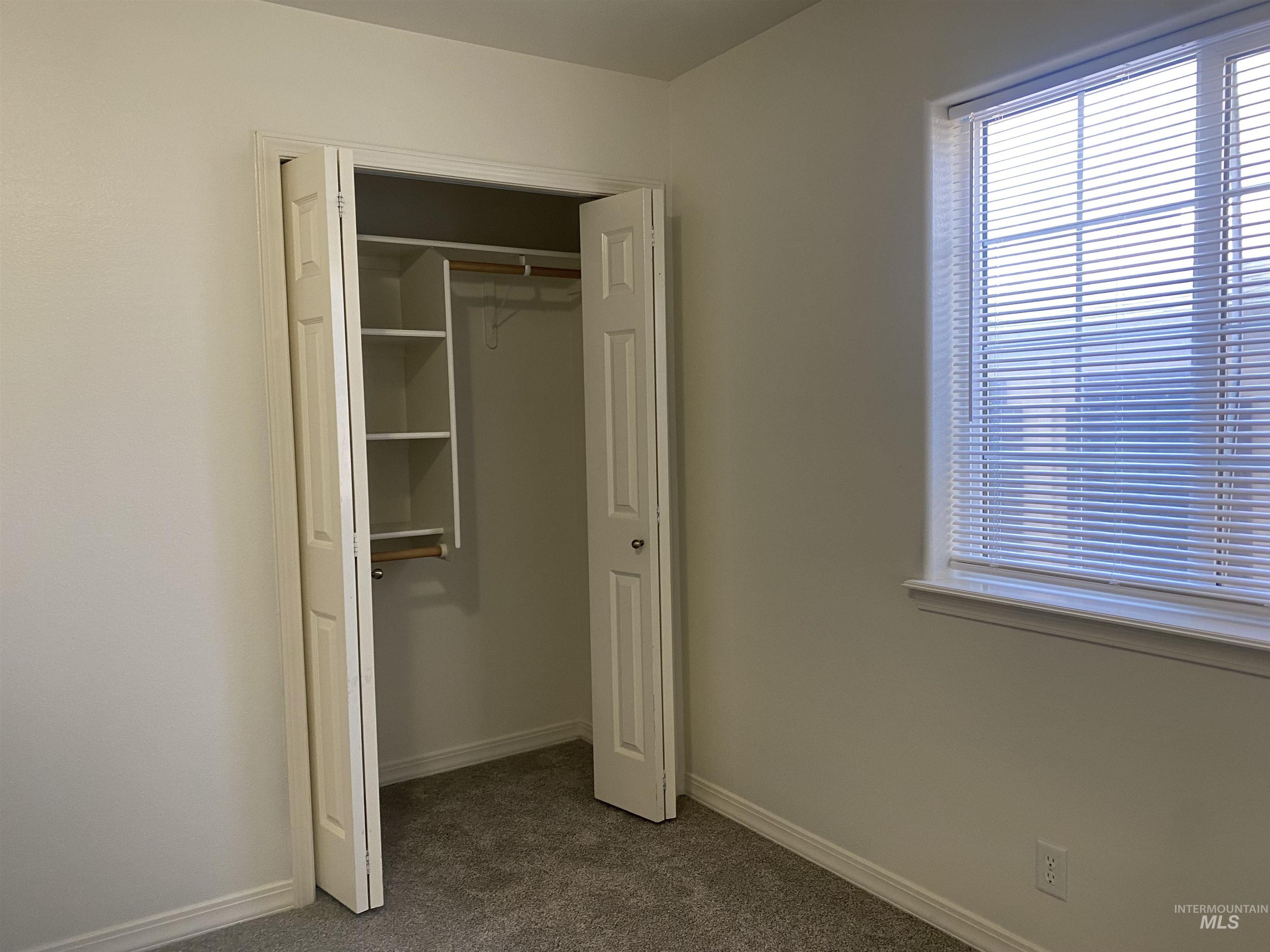 Unfurnished bedroom featuring dark colored carpet and a closet
