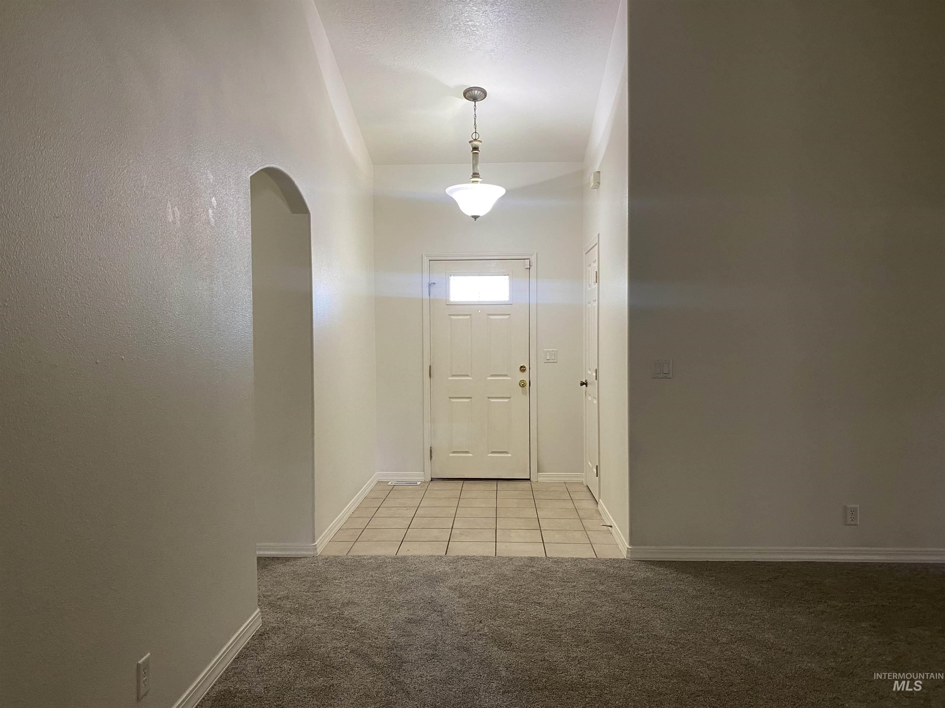 Entryway featuring tile patterned flooring, carpet floors, and arched walkways