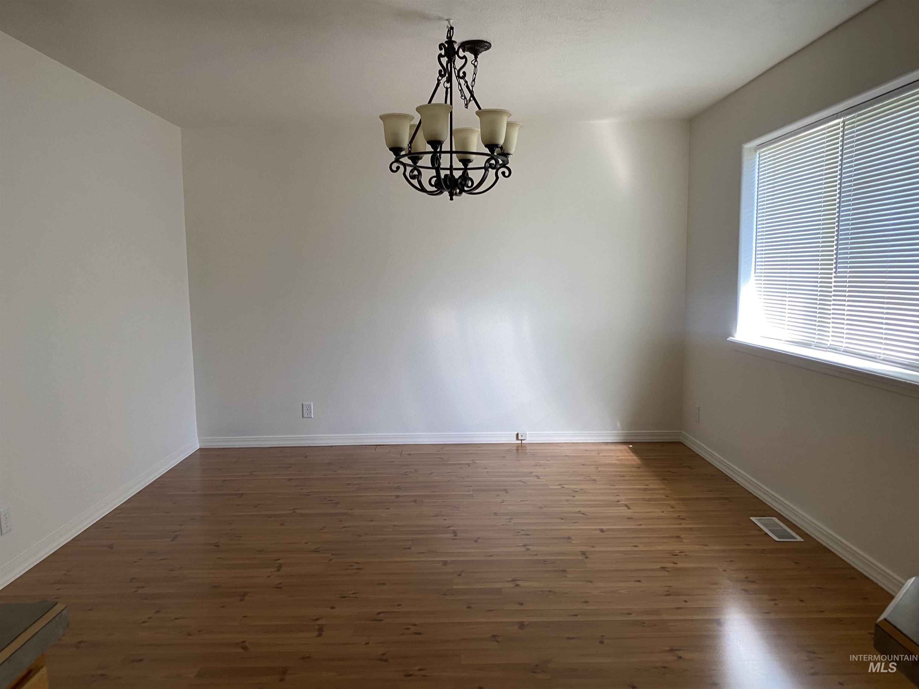 Unfurnished dining area featuring dark wood-type flooring and a chandelier