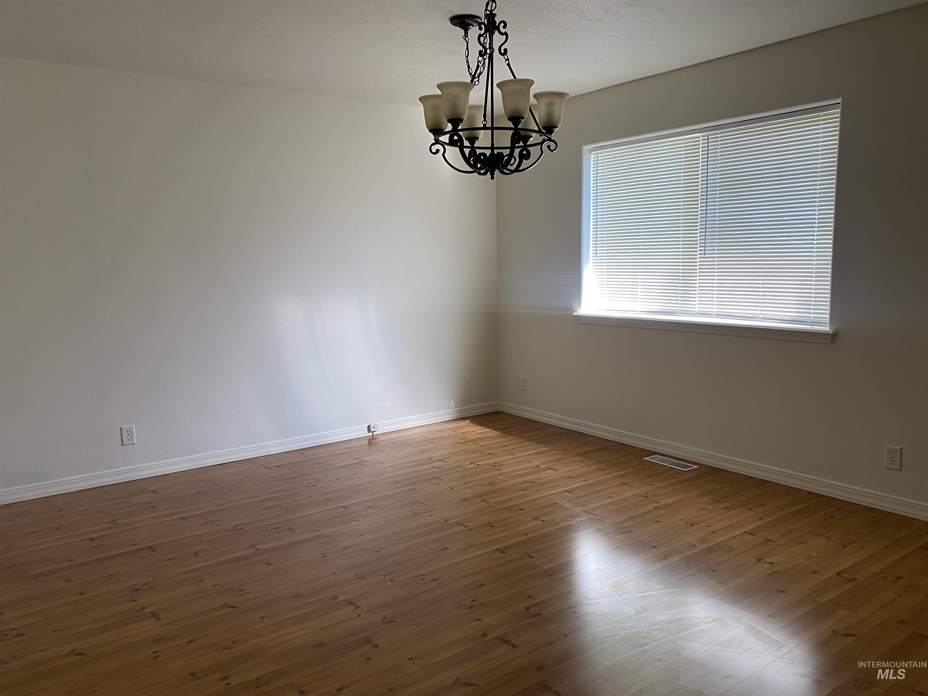 Empty room featuring wood finished floors and a chandelier