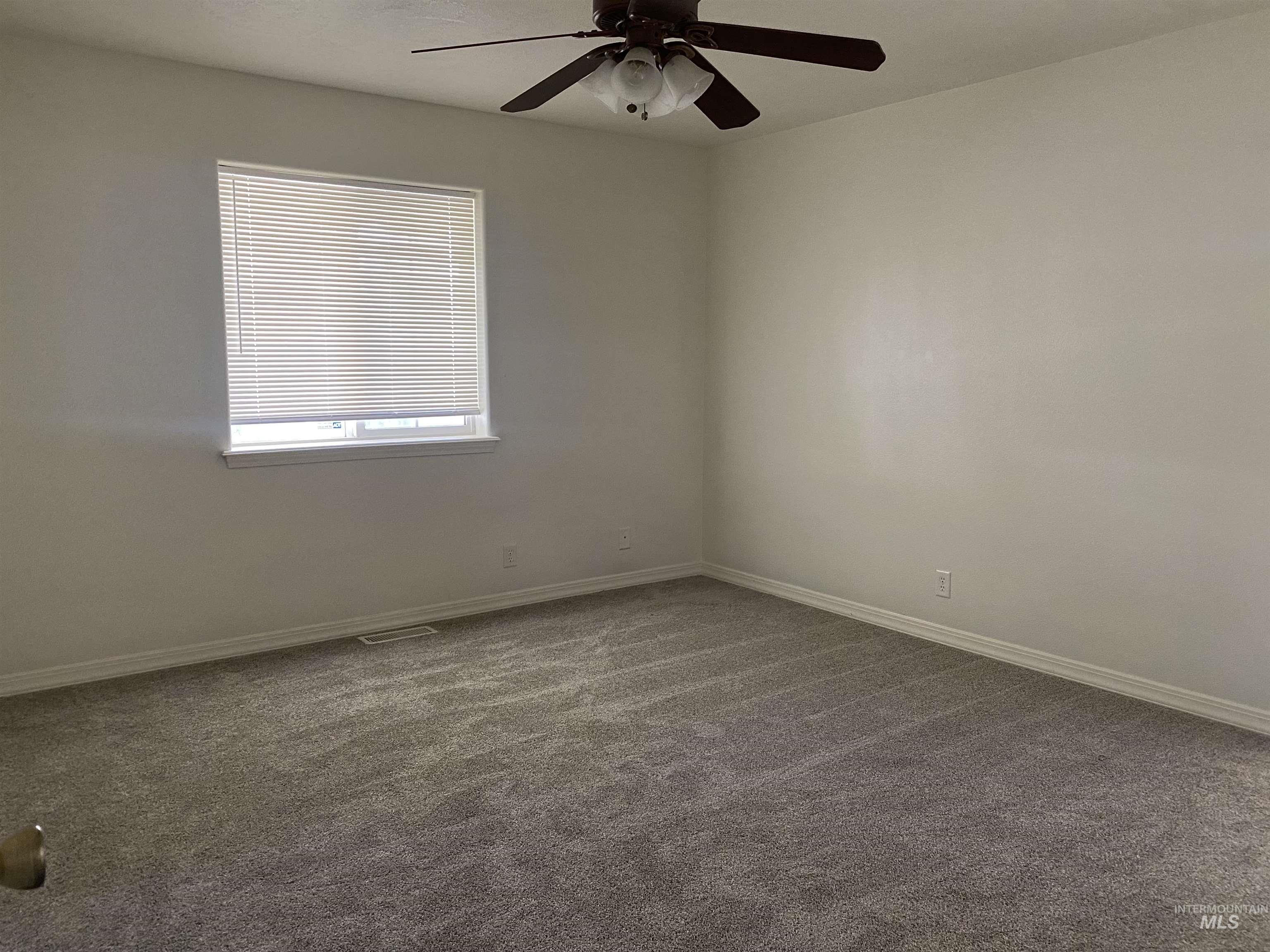 Unfurnished room featuring dark carpet and a ceiling fan