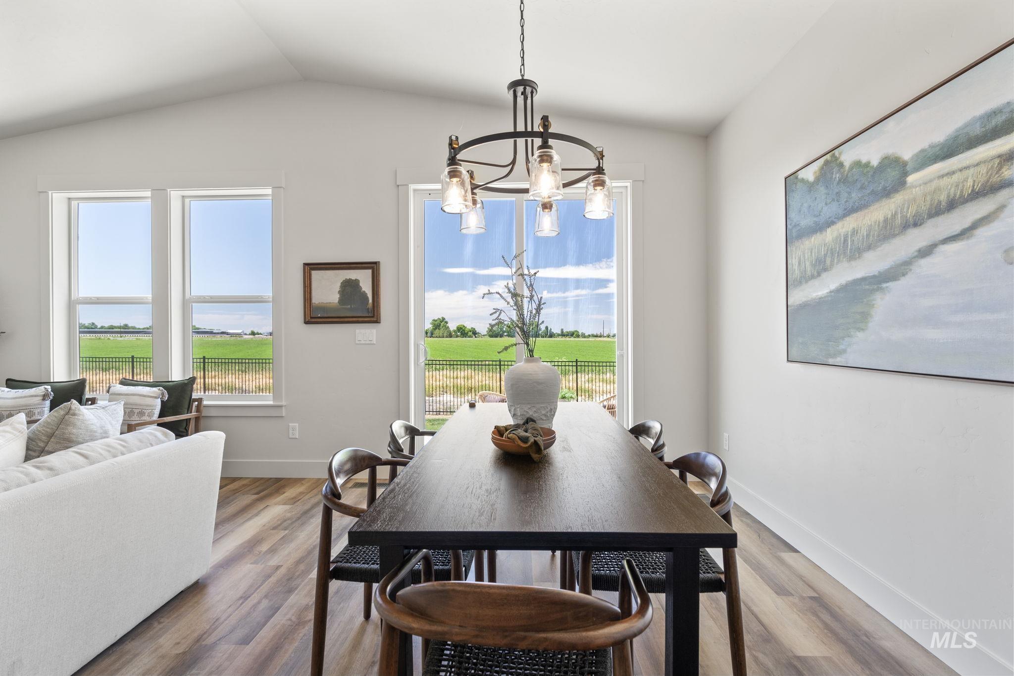 Dining room with a chandelier, wood finished floors, and lofted ceiling
