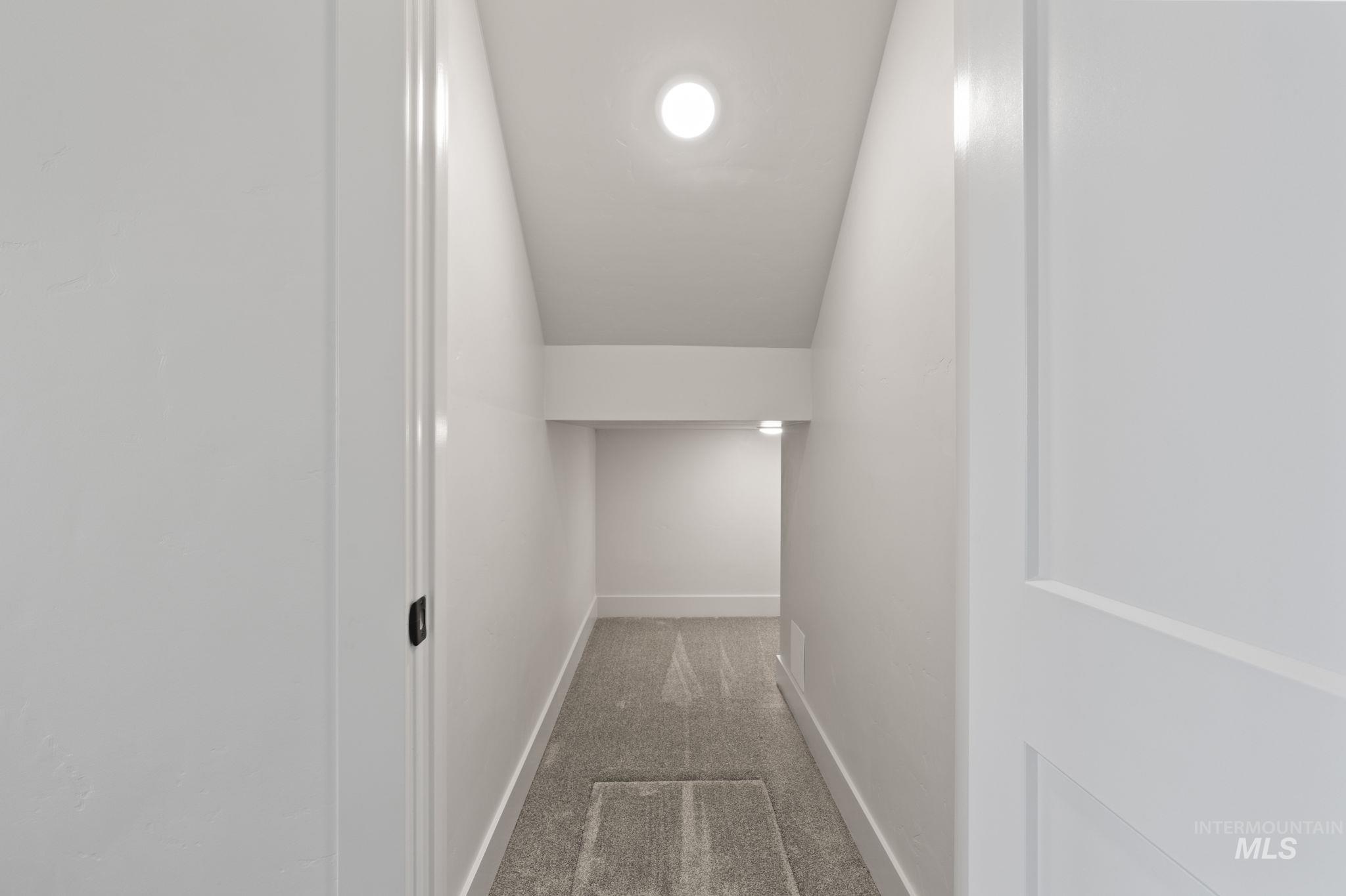 Hall with dark carpet and vaulted ceiling
