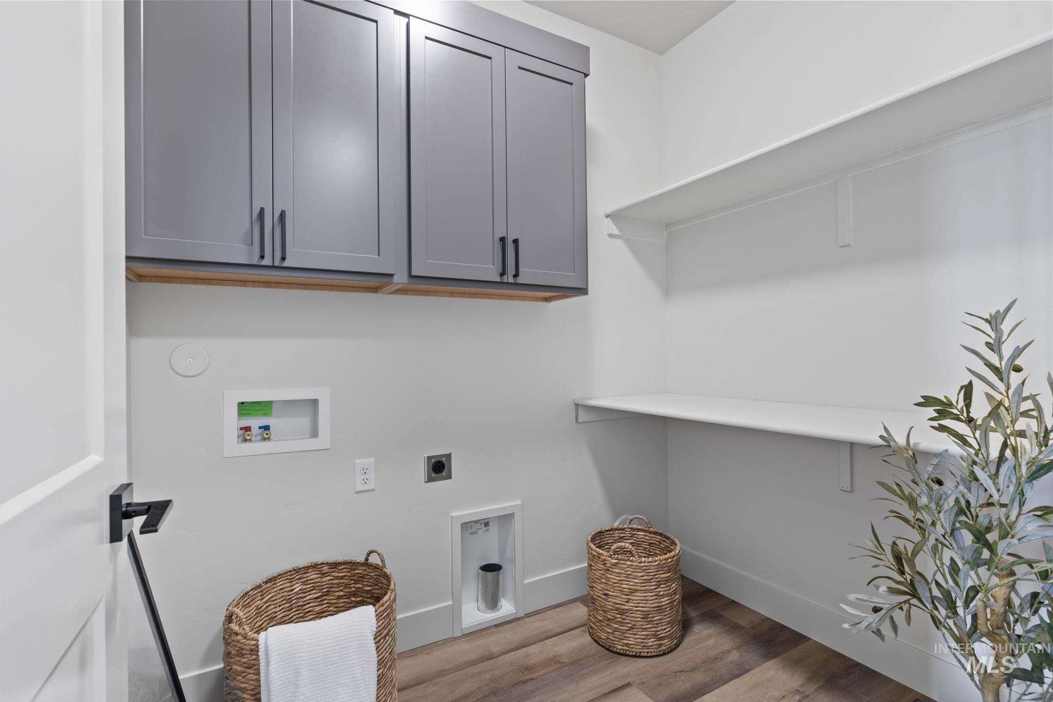 Laundry area featuring light wood-style floors, electric dryer hookup, hookup for a washing machine, and cabinet space