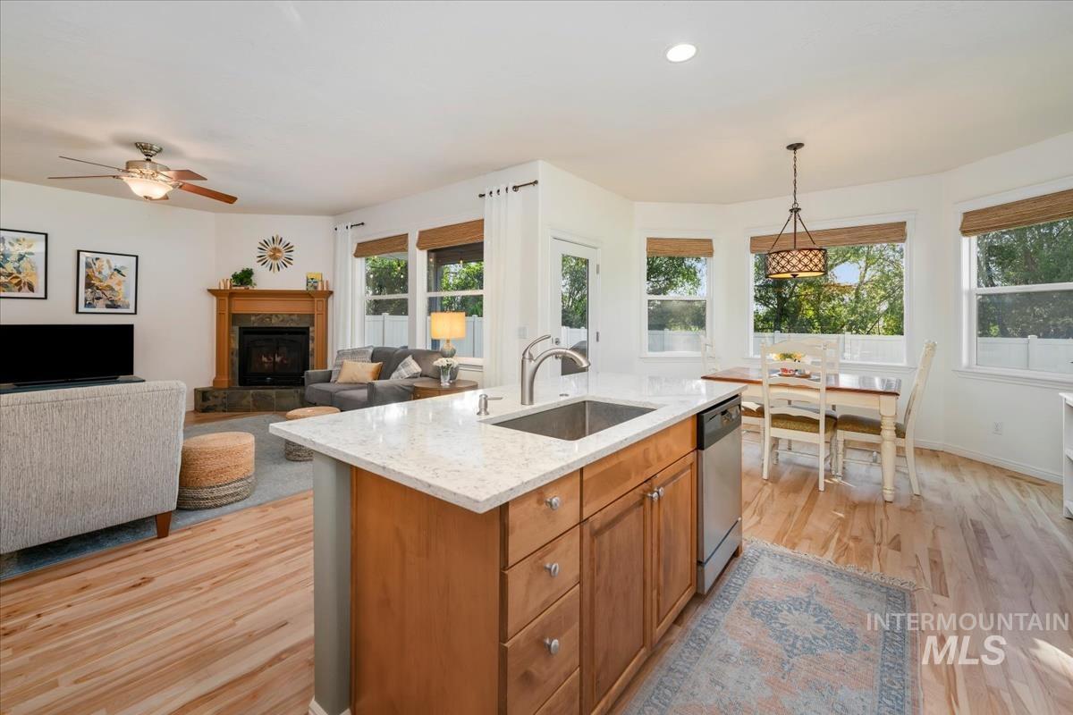 Kitchen with brown cabinets, hanging light fixtures, light stone counters, light wood-style flooring, and recessed lighting