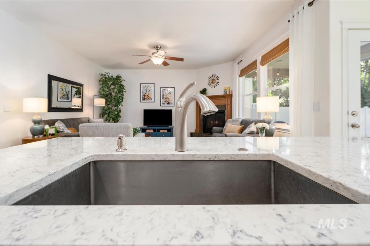Kitchen with open floor plan, light stone countertops, a fireplace, and ceiling fan