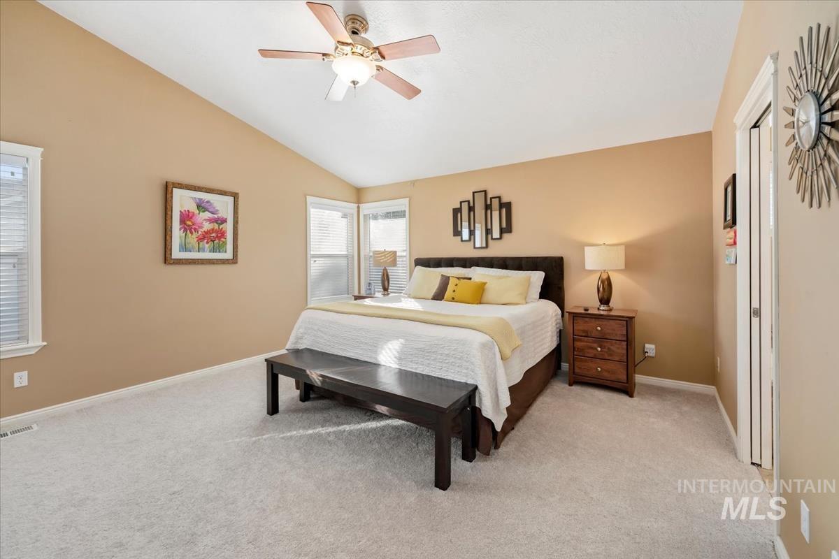 Bedroom featuring vaulted ceiling, light colored carpet, and a ceiling fan