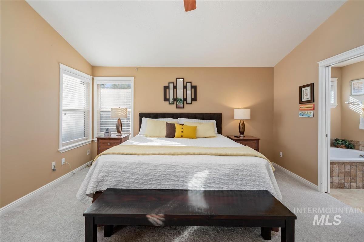 Carpeted bedroom with lofted ceiling and ceiling fan