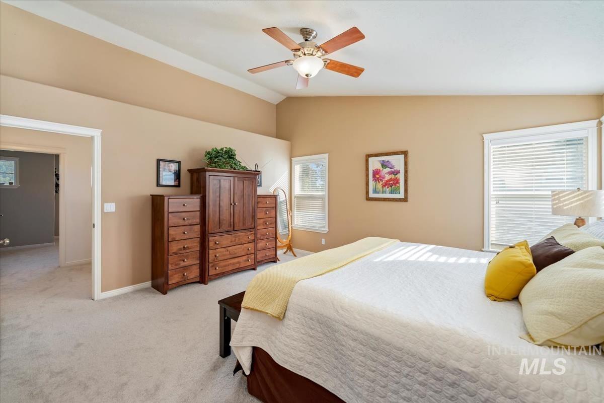 Bedroom with multiple windows, lofted ceiling, light colored carpet, and a ceiling fan