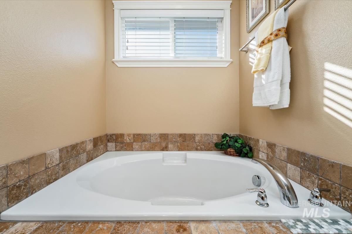 Bathroom featuring a garden tub and a textured wall