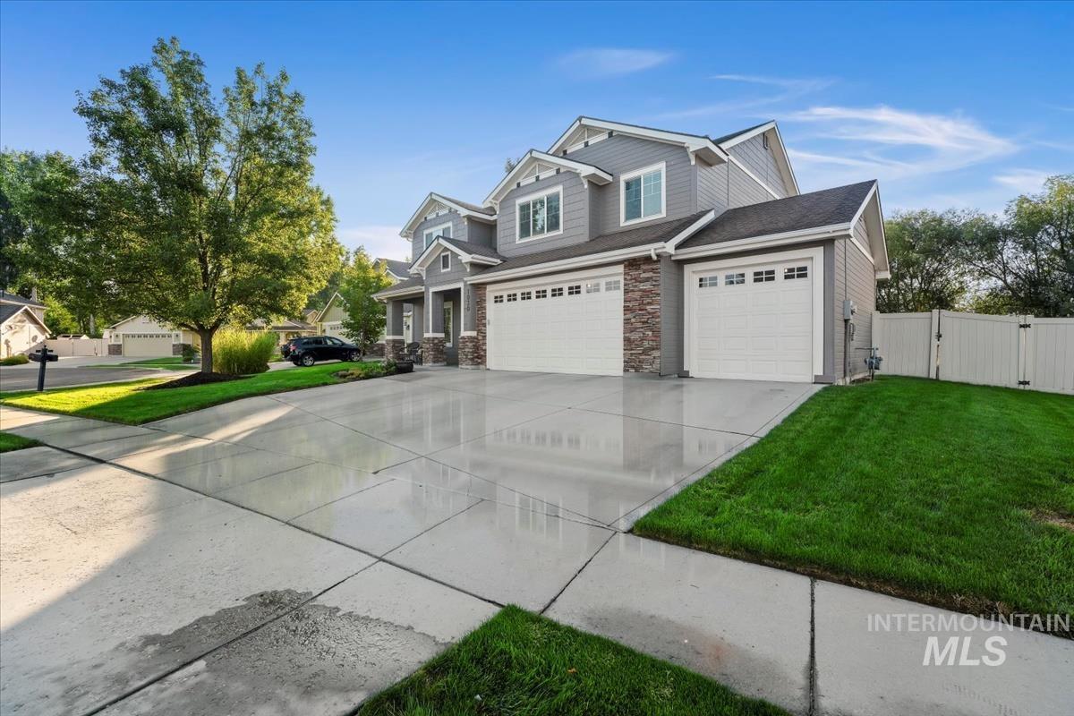 Craftsman house featuring a gate, concrete driveway, stone siding, roof with shingles, and an attached garage