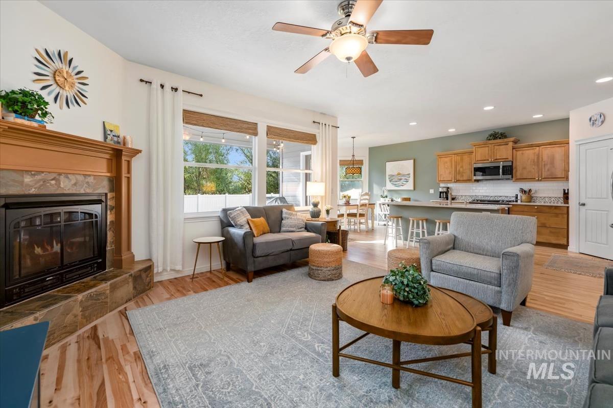 Living area featuring light wood-style floors, a premium fireplace, a ceiling fan, and recessed lighting