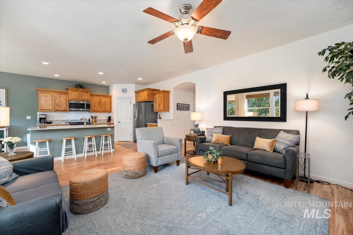 Living room with light wood-style floors, arched walkways, a ceiling fan, and recessed lighting