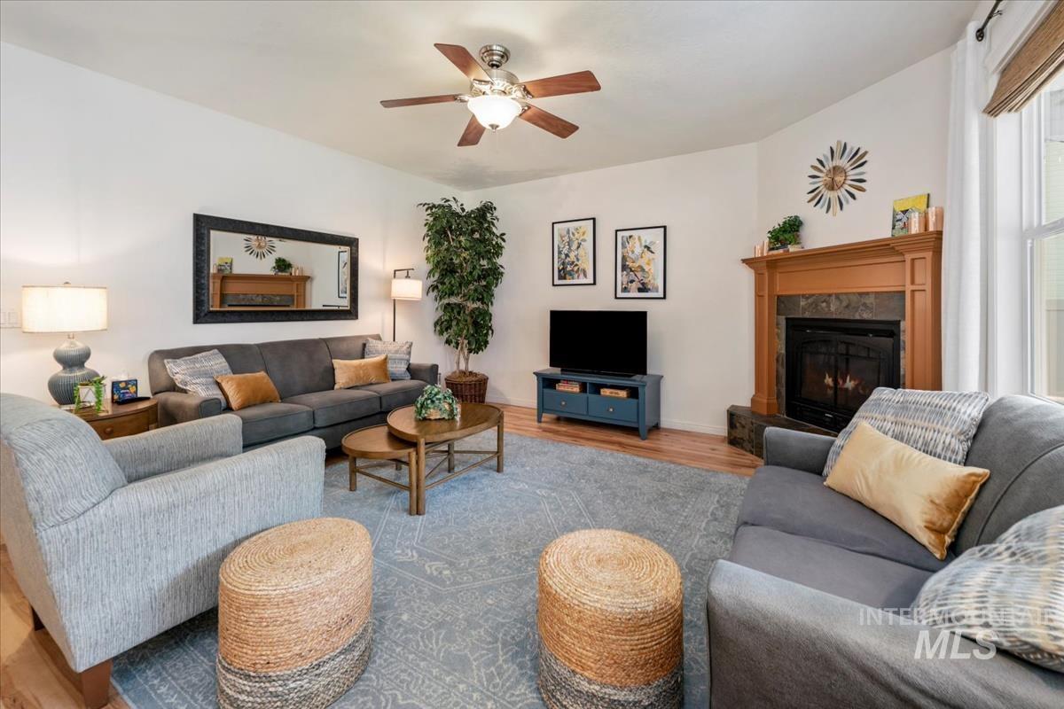 Living room featuring wood finished floors, a premium fireplace, and a ceiling fan