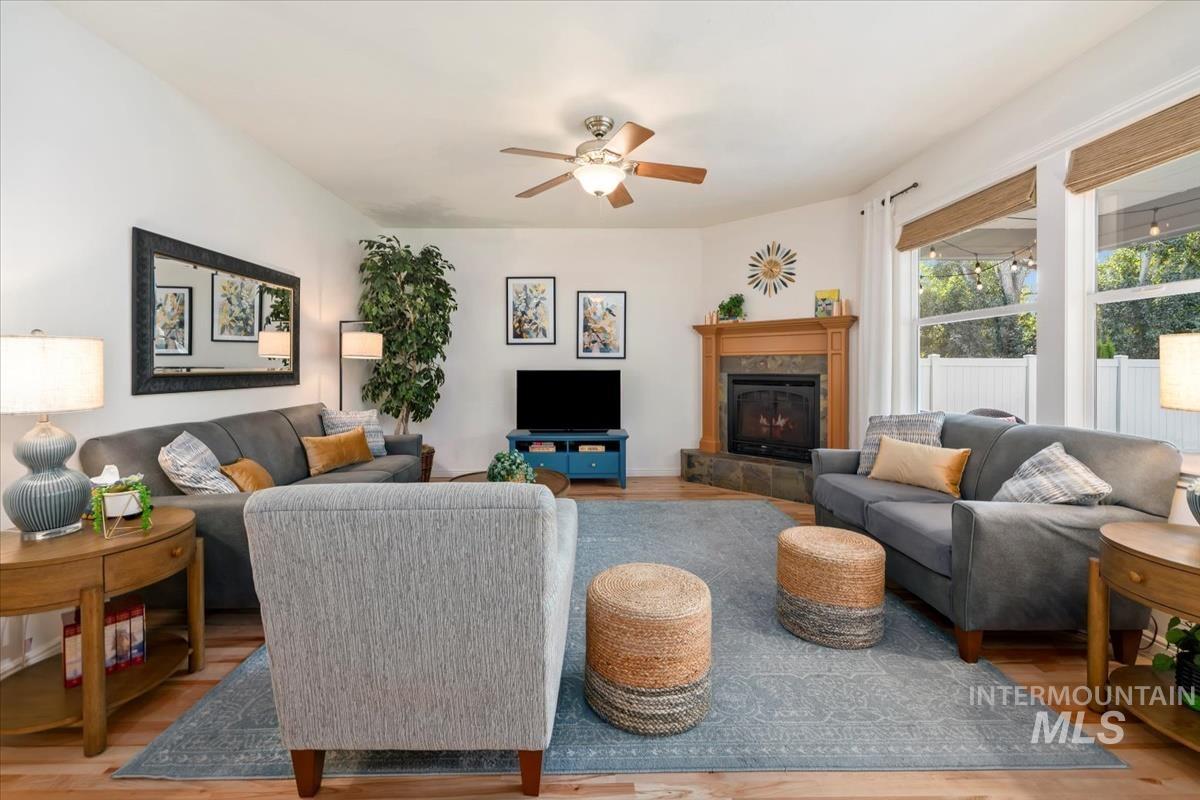 Living area with a tile fireplace, wood finished floors, and ceiling fan