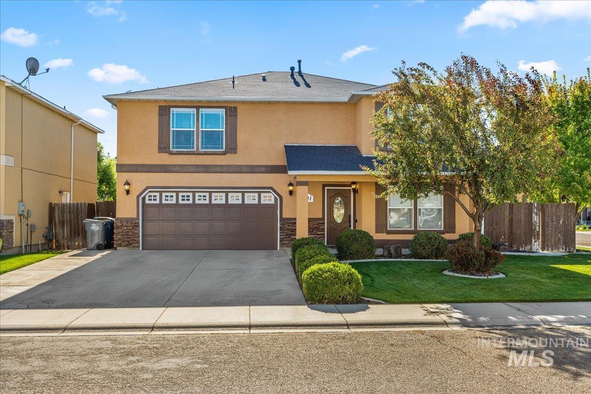 Traditional home with stucco siding, stone siding, concrete driveway, an attached garage, and a shingled roof