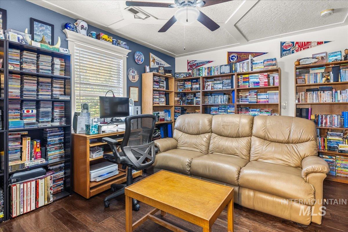 Office area with dark wood-style flooring, a ceiling fan, and a textured ceiling