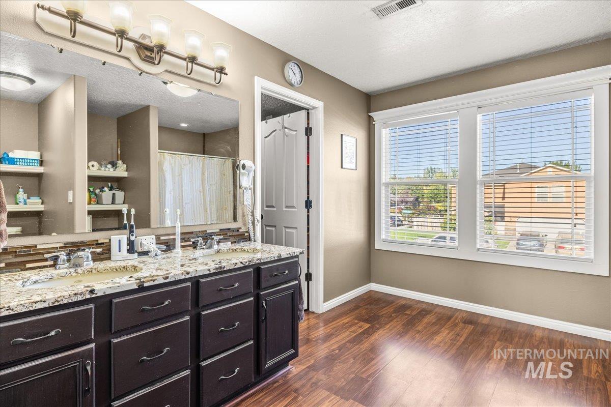 Bathroom with double vanity, dark wood-style flooring, a textured ceiling, and curtained shower