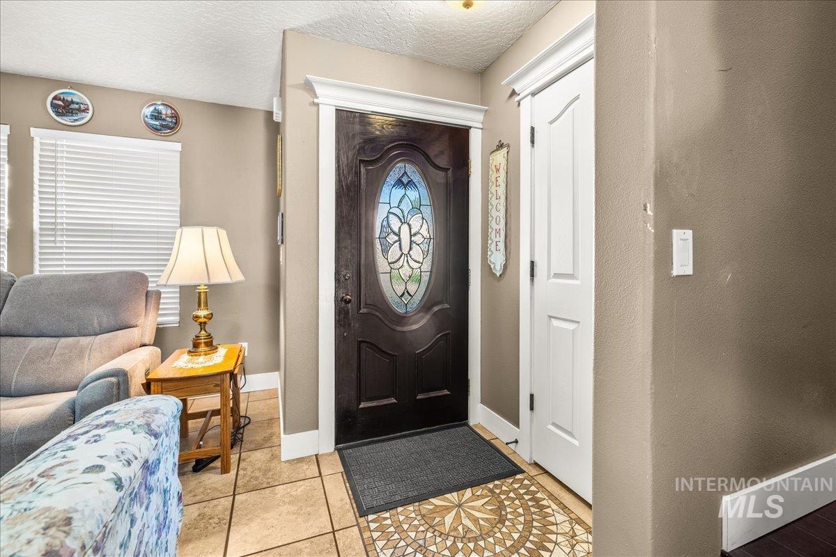 Entryway featuring light tile patterned floors and a textured ceiling